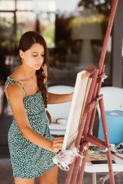 Jonge vrouwelijke kunstenaar schildert met een spatel op het doek