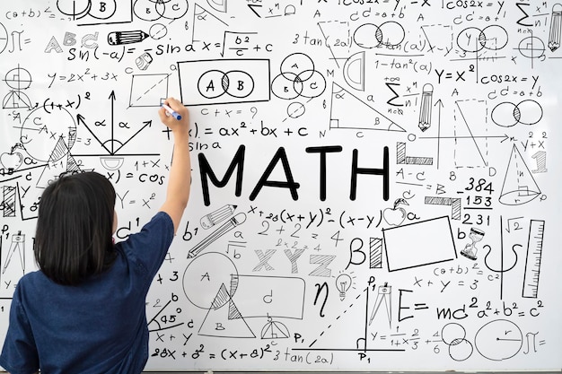 Jonge vrouwelijke leraar schrijft wiskundige formules en vergelijkingen op het whiteboard om educatief materiaal uit te leggen