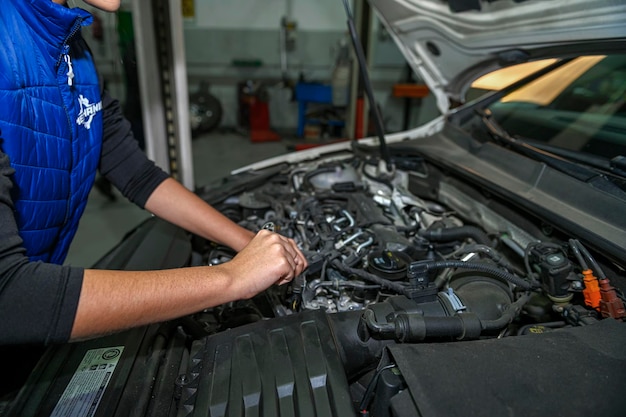 Jonge vrouwelijke monteur werkt aan de reparatie van een automotor
