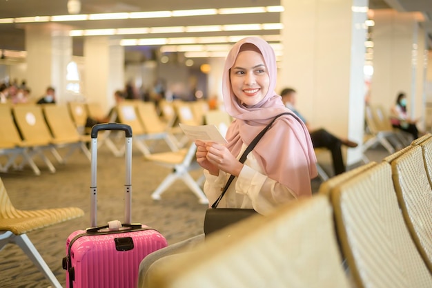 Jonge vrouwelijke moslimreiziger die koffers draagt bij de internationale luchthaven