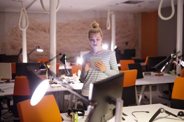 jonge vrouwelijke ondernemer werkt aan digitale tablet in nachtkantoor