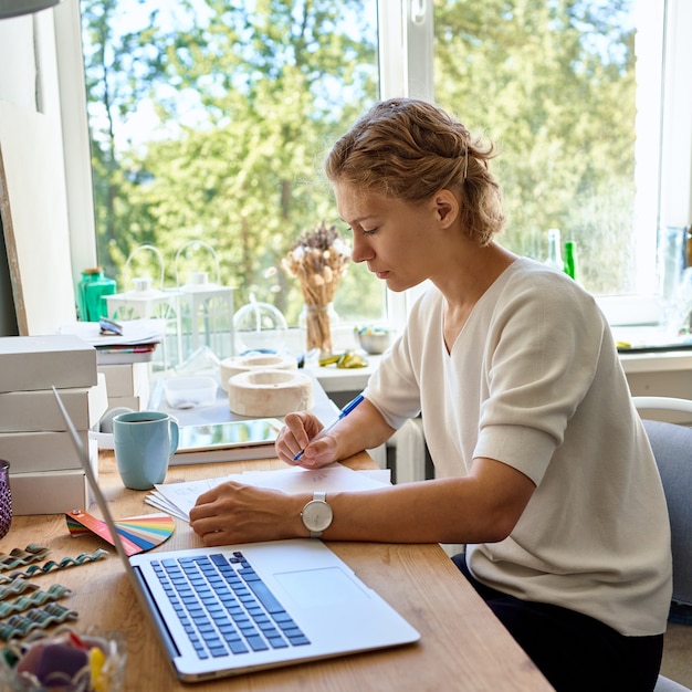 Jonge vrouwelijke ondernemersontwerper schrijven op vel papier, serieuze vrouw denken en plannen