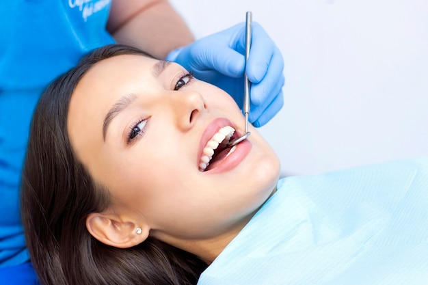 Jonge vrouwelijke patiënt met mooie glimlach die tandheelkundige inspectie onderzoekt in de tandartskliniek. Gezonde tanden en medicijnen, stomatologieconcept