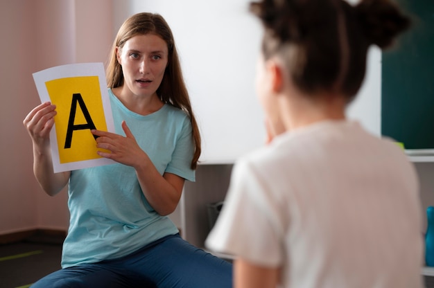 Jonge vrouwelijke psycholoog die een meisje helpt bij logopedie