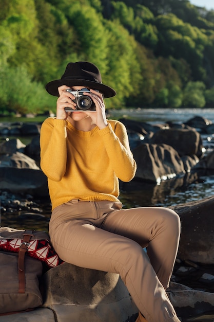 Jonge vrouwelijke reiziger maakt foto's van de natuur op retro camera