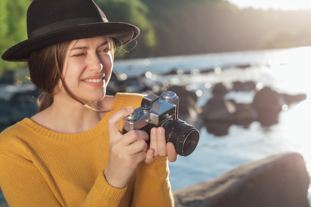 Jonge vrouwelijke reiziger maakt foto's van de natuur op retro camera