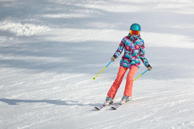 Jonge vrouwelijke skiër die op een zonnige dag in een bergresort van de helling leert glijden. Ruimte kopiëren