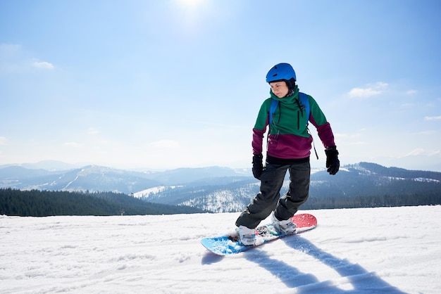 Jonge vrouwelijke snowboarder snowboard rijden op zonnige winterdag Wintersport en recreatie
