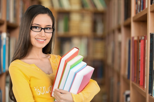 Jonge vrouwelijke student in bibliotheek.