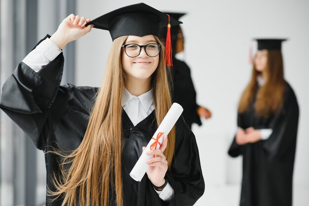 Jonge vrouwelijke student in gewaad viert haar afstuderen