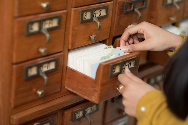 Jonge vrouwelijke student onderzoekt en leest boeken in de universitaire bibliotheek