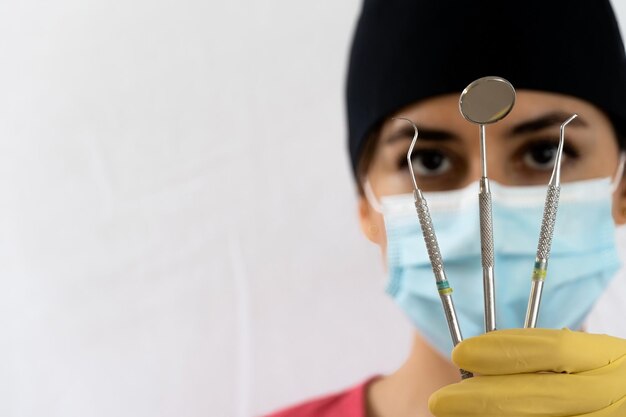 Foto jonge vrouwelijke tandarts met tandheelkundige instrumenten in haar hand