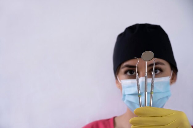 Jonge vrouwelijke tandarts met tandheelkundige instrumenten in haar hand