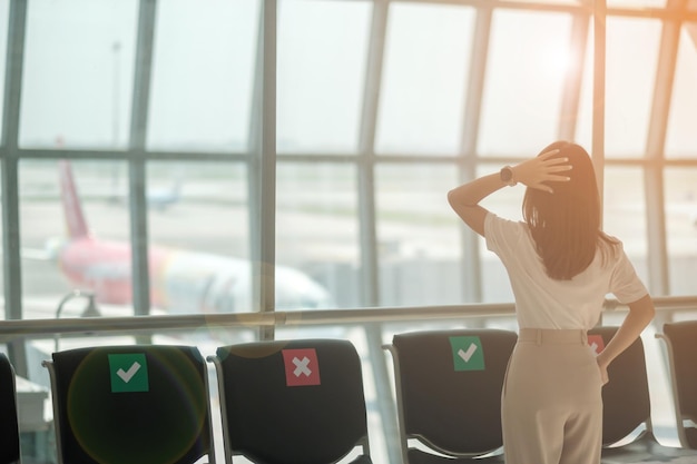 Jonge vrouwelijke toerist bij de internationale luchthaventerminal Tijd om reis- en vakantieconcepten te reizen