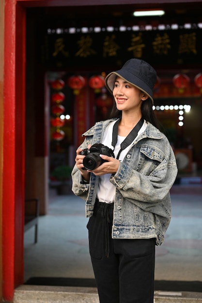 Jonge vrouwelijke toerist die camera vasthoudt in de traditionele Azië-tempel