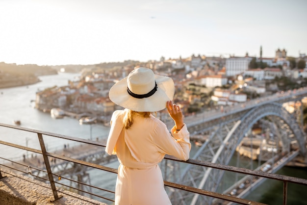 Jonge vrouwelijke toerist die geniet van een prachtig luchtfoto stadsgezicht met de beroemde brug tijdens de zonsondergang in de stad Porto, Portugal