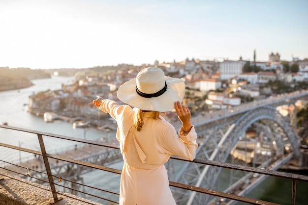 Jonge vrouwelijke toerist die geniet van een prachtig luchtfoto stadsgezicht met de beroemde brug tijdens de zonsondergang in de stad Porto, Portugal