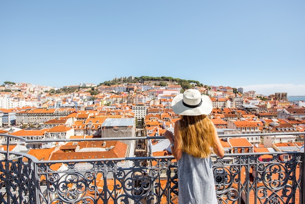 Jonge vrouwelijke toerist die geniet van een prachtig stadsgezicht bovenaanzicht op de oude stad tijdens de zonnige dag in de stad Lissabon, Portugal