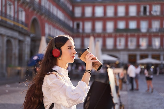 Jonge vrouwelijke toerist die naar muziek luistert en door de straten van Madrid loopt