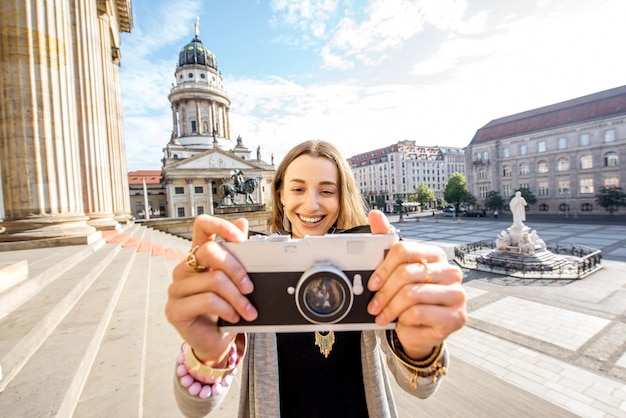 Jonge vrouwelijke toerist die plezier heeft met een fotocamera in de buurt van het concertgebouw in de stad Berlijn