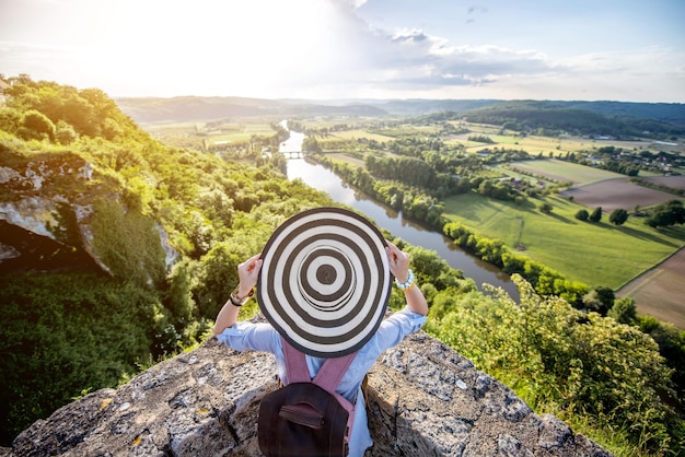 Jonge vrouwelijke toerist in hoed die geniet van zonsondergang op het prachtige landschap met de rivier de Dordogne in Frankrijk