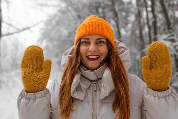 Foto jonge vrouwelijke toerist in warme kleren en gele handschoenen die een selfie maakt tijdens een winterstein in de stad op de berg