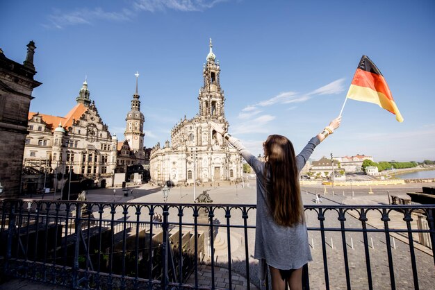 Jonge vrouwelijke toerist met duitse vlag die geniet van een prachtig uitzicht op de schlossplatz in de stad dresden tijdens het ochtendlicht