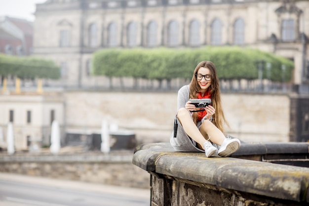 Jonge vrouwelijke toerist met fotocamera die geniet van een geweldig uitzicht vanaf de brug over de oude stad van Dresden in Duitsland