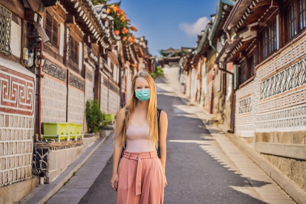 Jonge vrouwelijke toerist met medisch masker in het dorp bukchon hanok is een van de bekendste plekken voor koreanen