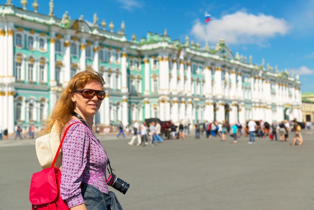 Jonge vrouwelijke toerist passeert het Winterpaleis in Sint-Petersburg