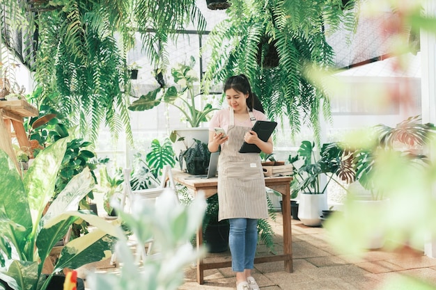 Jonge vrouwelijke tuinman staat in de tuin om contact op te nemen met klanten