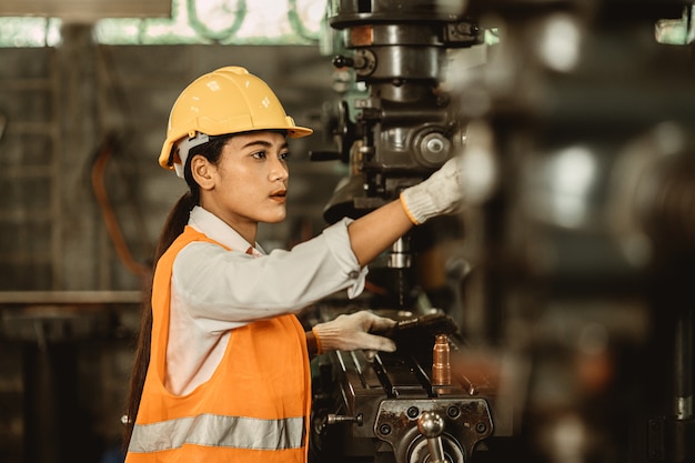 Jonge vrouwelijke vrouwen wonen een werknemer bij die graag werkt in een metaalfabriek, een werkingenieur, een machine voor het onderhoud van de zware industrie.