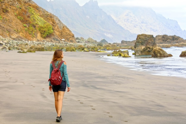 Jonge vrouwelijke wandelaar die wild paradijselijk strand op het eiland Tenerife ontdekt