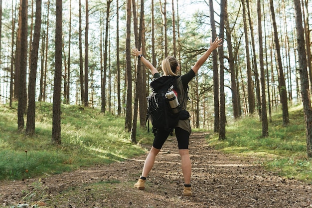 Jonge vrouwelijke wandelaar met grote rugzak in groen bos