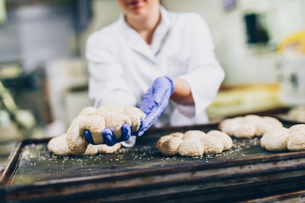 Jonge vrouwelijke werknemer die in grote bakkerij werkt. brood bereiding.
