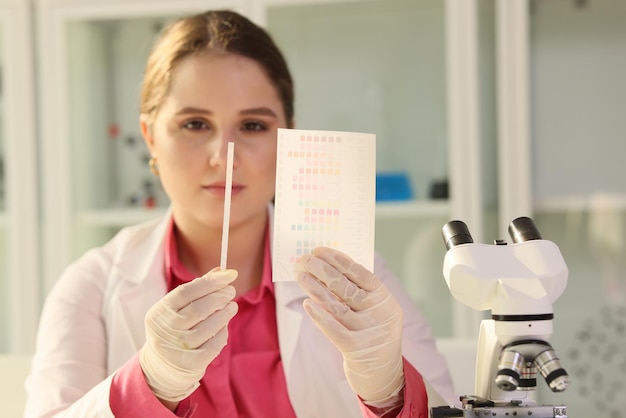 Jonge vrouwelijke wetenschapper die de resultaten van experimenten beoordeelt en naar papier kijkt met monsters erin