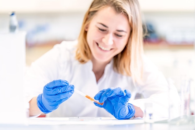 Jonge vrouwelijke wetenschapper met een glimlach op haar gezicht test een nieuwe uitvinding in een onderzoekslaboratorium