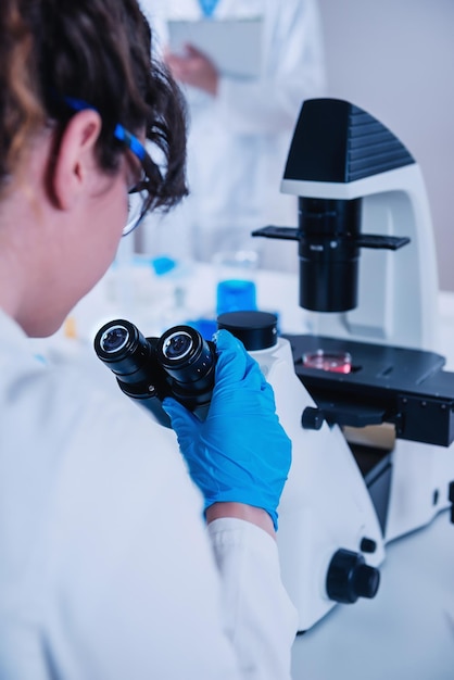 Foto jonge vrouwelijke wetenschapper met een microscoop in het laboratorium