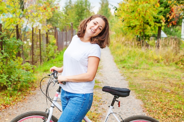 Jonge vrouwen berijdende fiets in het park van de de zomerstad in openlucht. Actieve mensen. Het Hipstermeisje ontspant en ruiterfiets. Op de zomerdag naar het werk fietsen. Fiets en ecologie levensstijl concept.