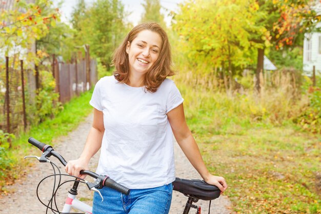 Jonge vrouwen berijdende fiets in het park van de de zomerstad in openlucht. Actieve mensen. Het Hipstermeisje ontspant en ruiterfiets. Op de zomerdag naar het werk fietsen. Fiets en ecologie levensstijl concept.