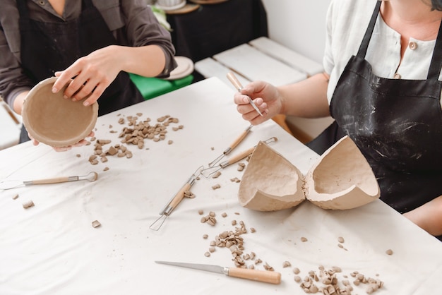 Jonge vrouwen die aarden pot in aardewerkworkshop maken