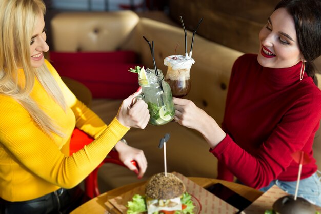 Jonge vrouwen die cocktailglazen roosteren