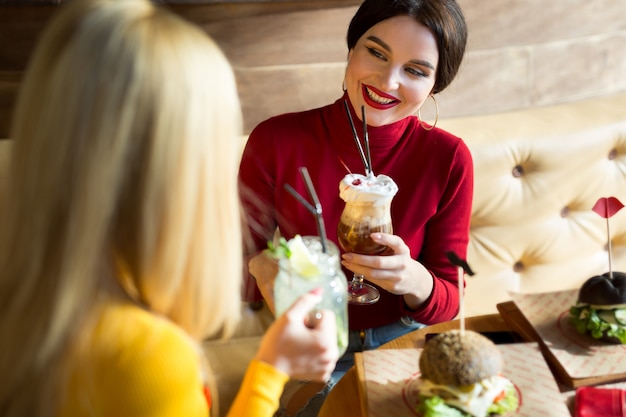 Jonge vrouwen die cocktailglazen roosteren