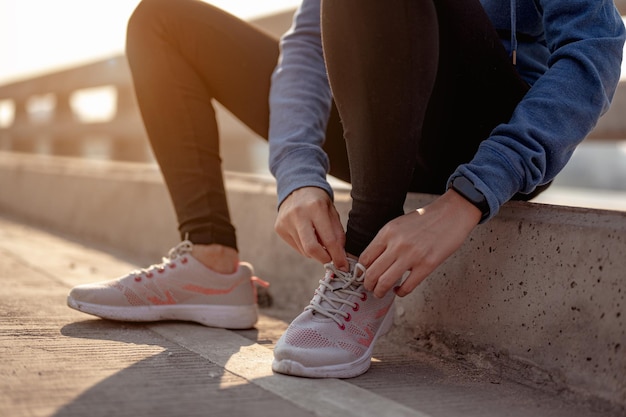 Jonge vrouwen die hun handen gebruiken om hun schoenen te binden die joggen in de ochtendtraining in de stad. een stad die gezond leeft in de hoofdstad. oefening, fitness, joggen, hardlopen, levensstijl, gezond concept.