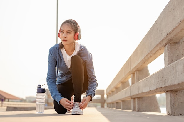 Jonge vrouwen die hun handen gebruiken om hun schoenen te binden die joggen in de ochtendtraining in de stad. Een stad die gezond leeft in de hoofdstad. Oefening, fitness, joggen, hardlopen, levensstijl, gezond concept.