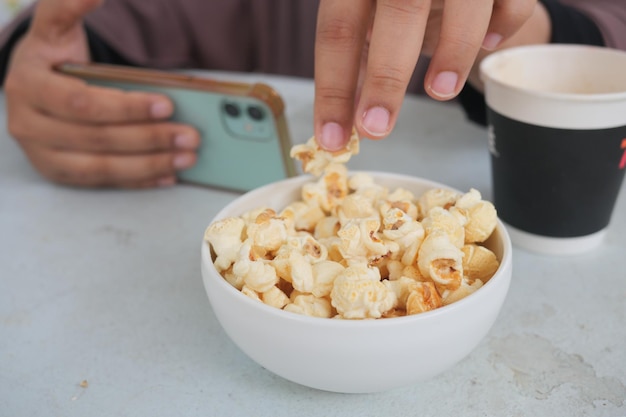 Jonge vrouwen die popcorn eten en een slimme telefoon vasthouden