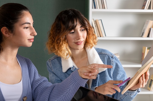 Foto jonge vrouwen die samen studeren uit een notitieboekje