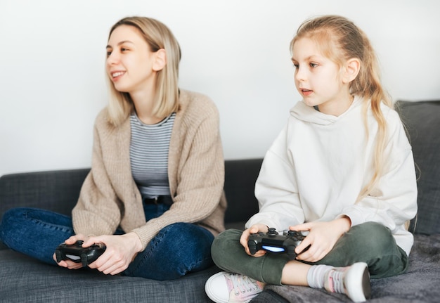 Jonge vrouwen en een klein meisje spelen graag videogames met de controllerconsole