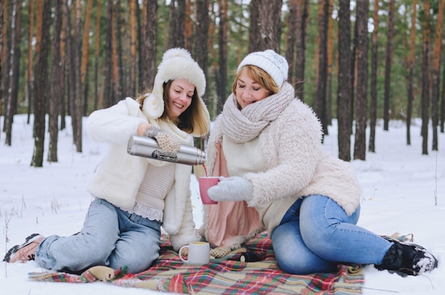 jonge vrouwen, haar moeder, wandelen in het ijzige winterpark. Plezier hebben. Koffie drinken. kersttijd