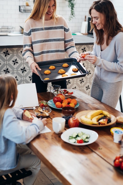 Jonge vrouwen in de keuken koken, koekjes bakken.